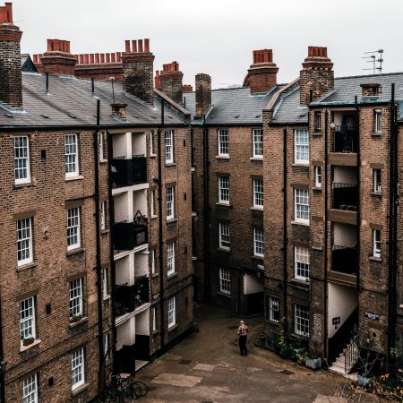 Aerial view of a moody, brick residential complex with multiple buildings featuring architectural details like chimneys and balconies. These buildings constructed before 1980 will have asbestos as part of their construction. 